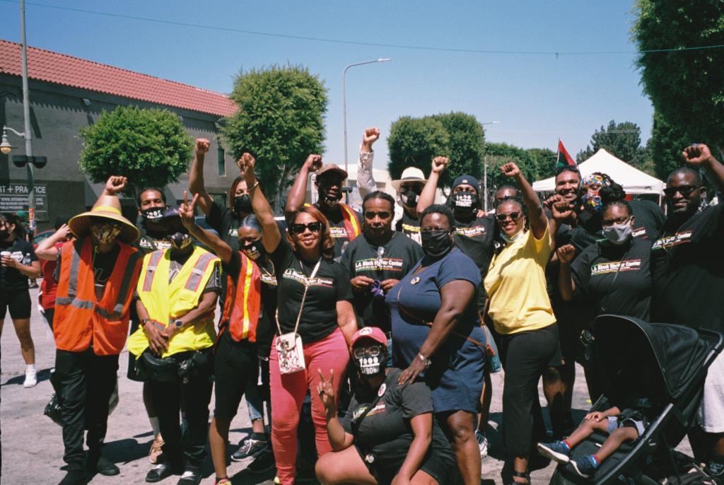 A group of Black workers pose on the street with fists in the air